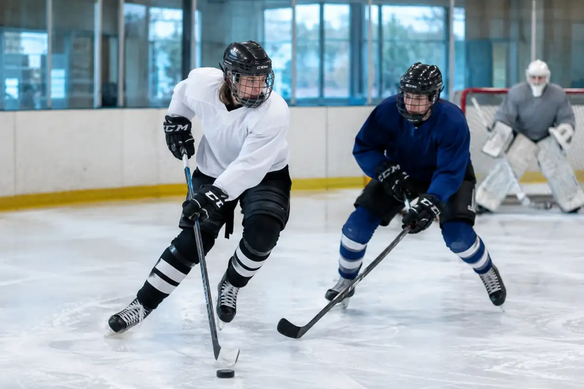 Deux joueurs en équipement disputent le palet sur la glace lors d’un match de hockey sur glace en patinoire.