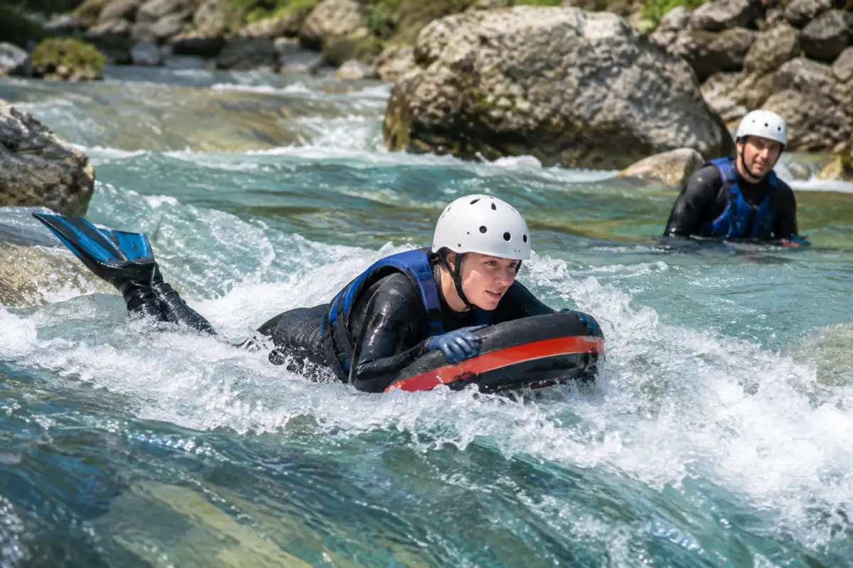 Pratiquant d’hydrospeed équipé d’un flotteur, de palmes, d’un casque et d’une combinaison dans un rapide de rivière.