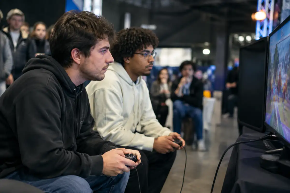 Deux joueurs s’affrontent sur un jeu vidéo de combat en tournoi, manette en main, dans une salle française.