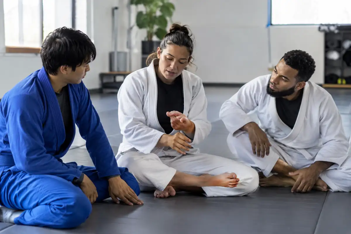 Un professeur montre le signal d’arrêt à une personne débutante sur le tapis propre d’un cours de jiu-jitsu brésilien.