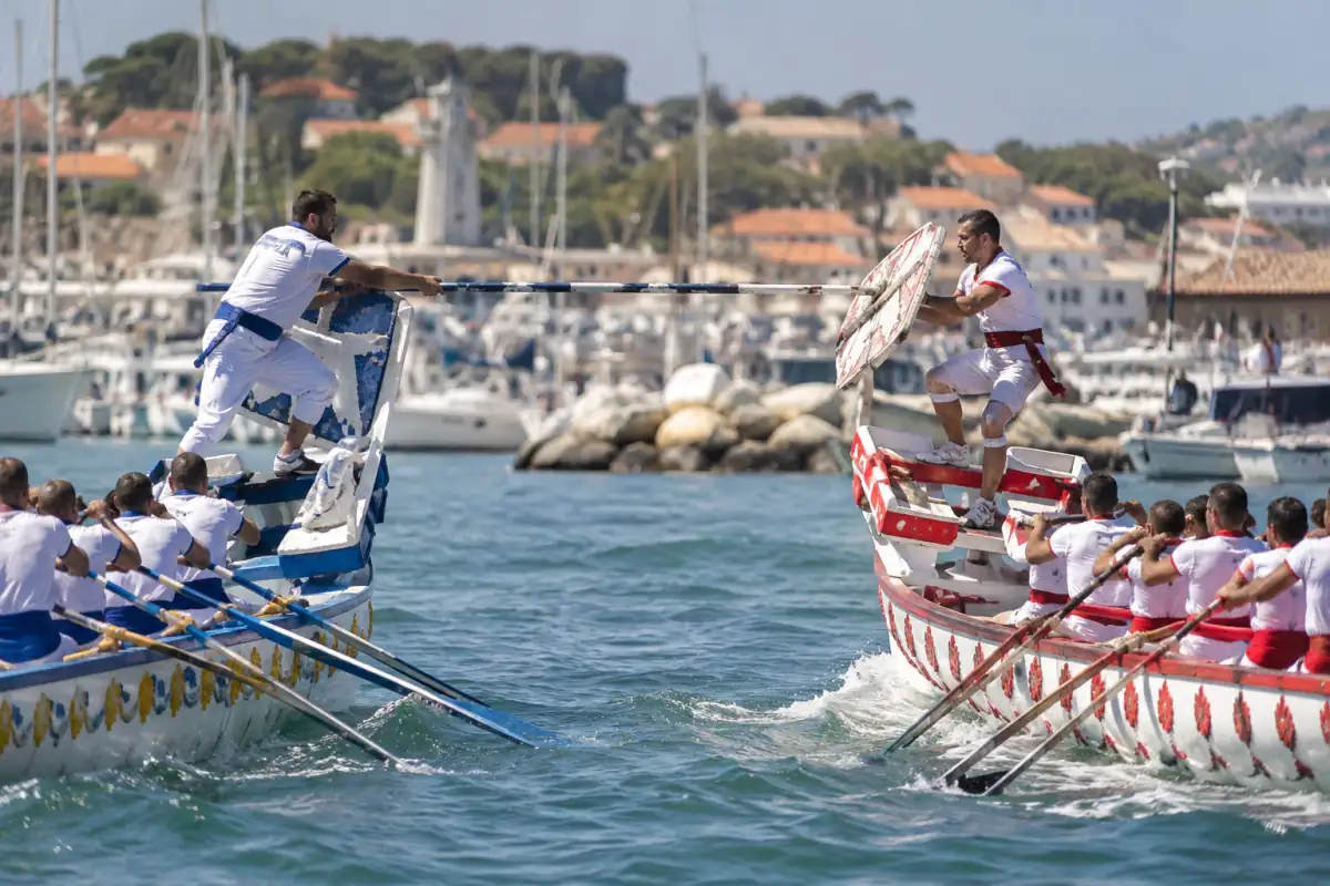 Jouteurs provençaux face à face sur leurs barques, lance et pavois en main lors d’une passe dans un port du sud de la France.