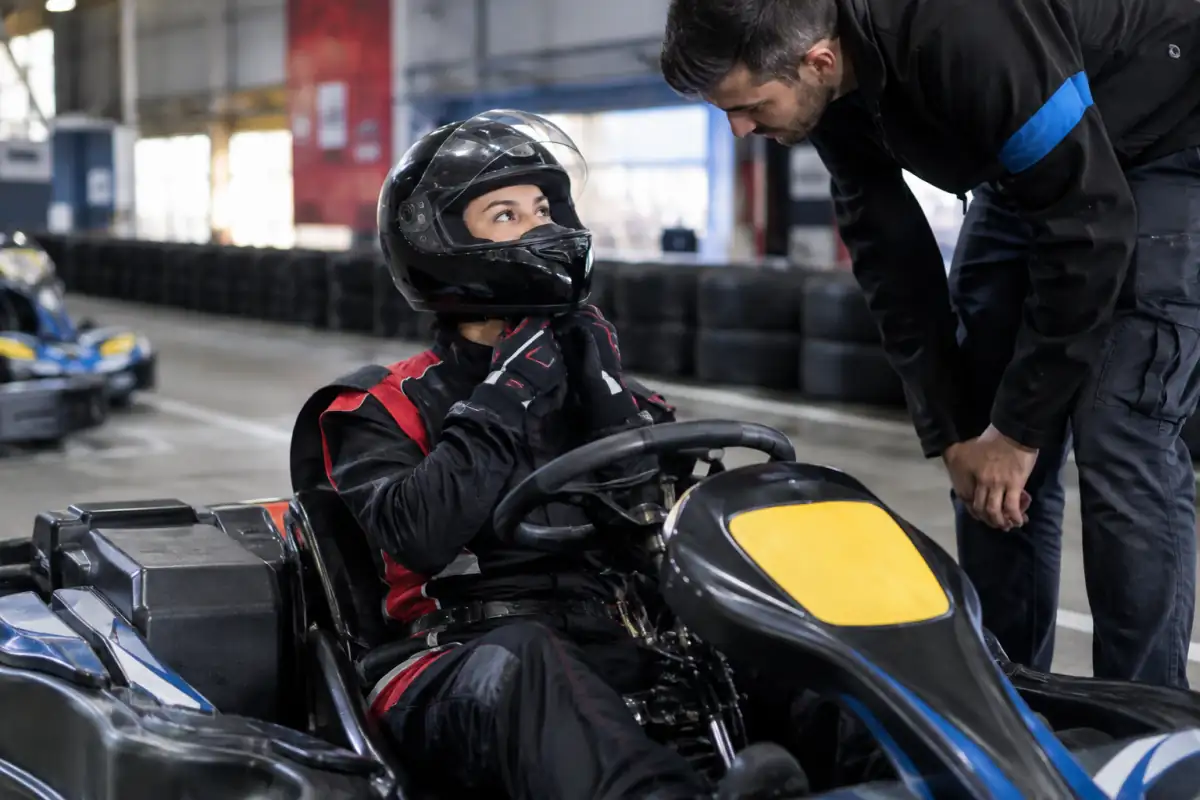 Pilote amateur ajustant son casque intégral, ses gants et sa combinaison avant une séance de karting sur un circuit.