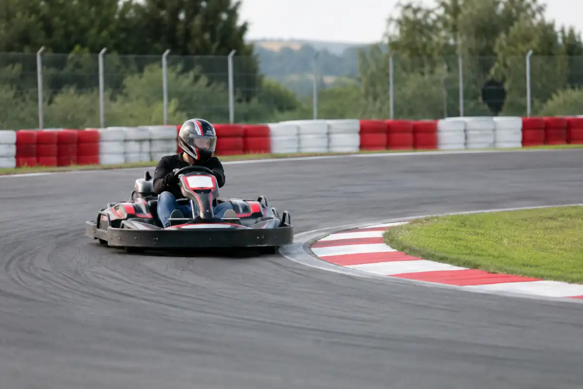 Pilote de kart de location vise la corde d’un virage, le regard déjà tourné vers la sortie de piste.