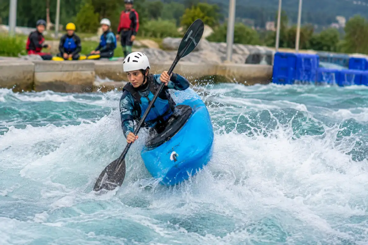 Kayakiste en équipement d’eau vive qui réalise une figure dans une vague stationnaire lors d’une séance de kayak freestyle.