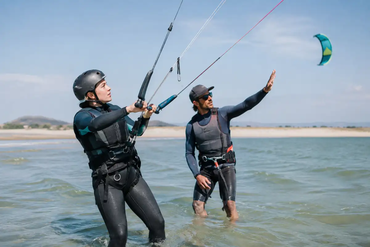 Débutant en kitesurf encadré par un moniteur dans l’eau, avec casque et gilet, pendant un exercice de pilotage.