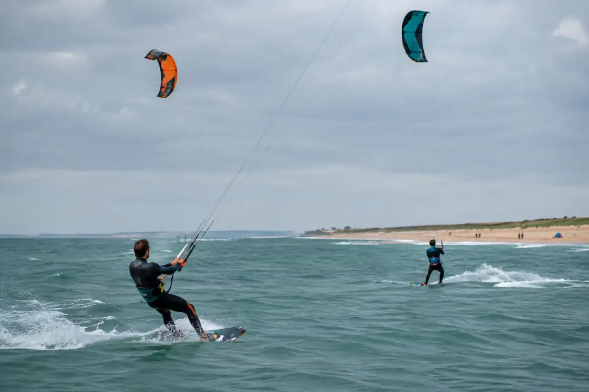 Deux kitesurfeurs anticipent un croisement en gardant leurs ailes à des hauteurs différentes et une marge de sécurité.