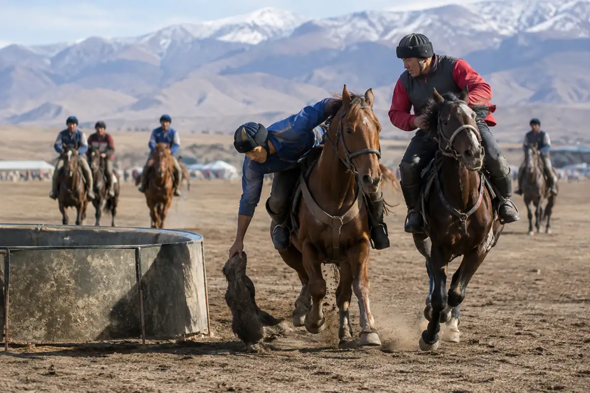 Des cavaliers kirghiz disputent un kok-boru à cheval et tentent de saisir l’ulak près d’un kazan sur un terrain extérieur.