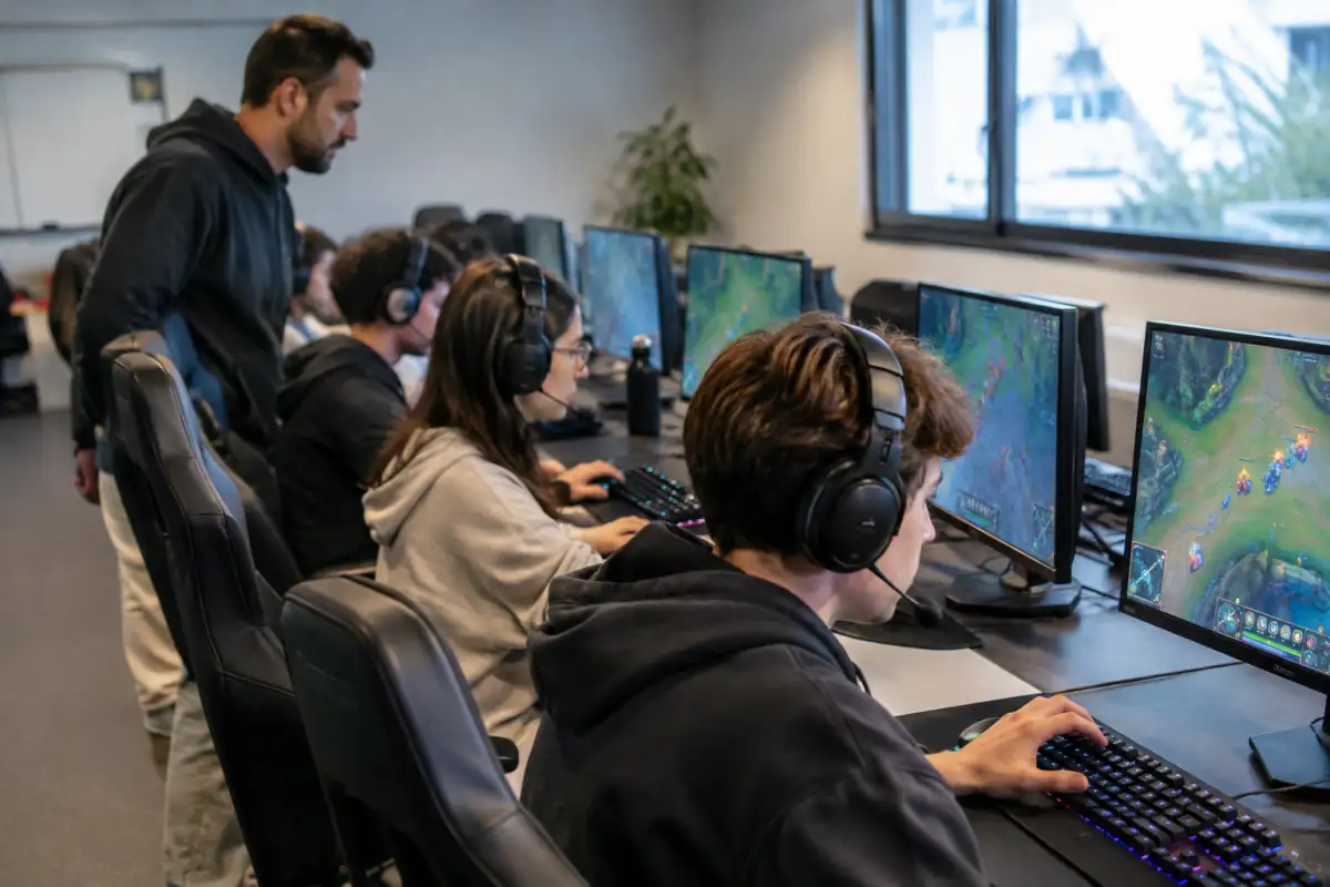 Joueurs de MOBA concentrés devant leurs écrans, coordonnant une partie en équipe dans une salle d’entraînement.