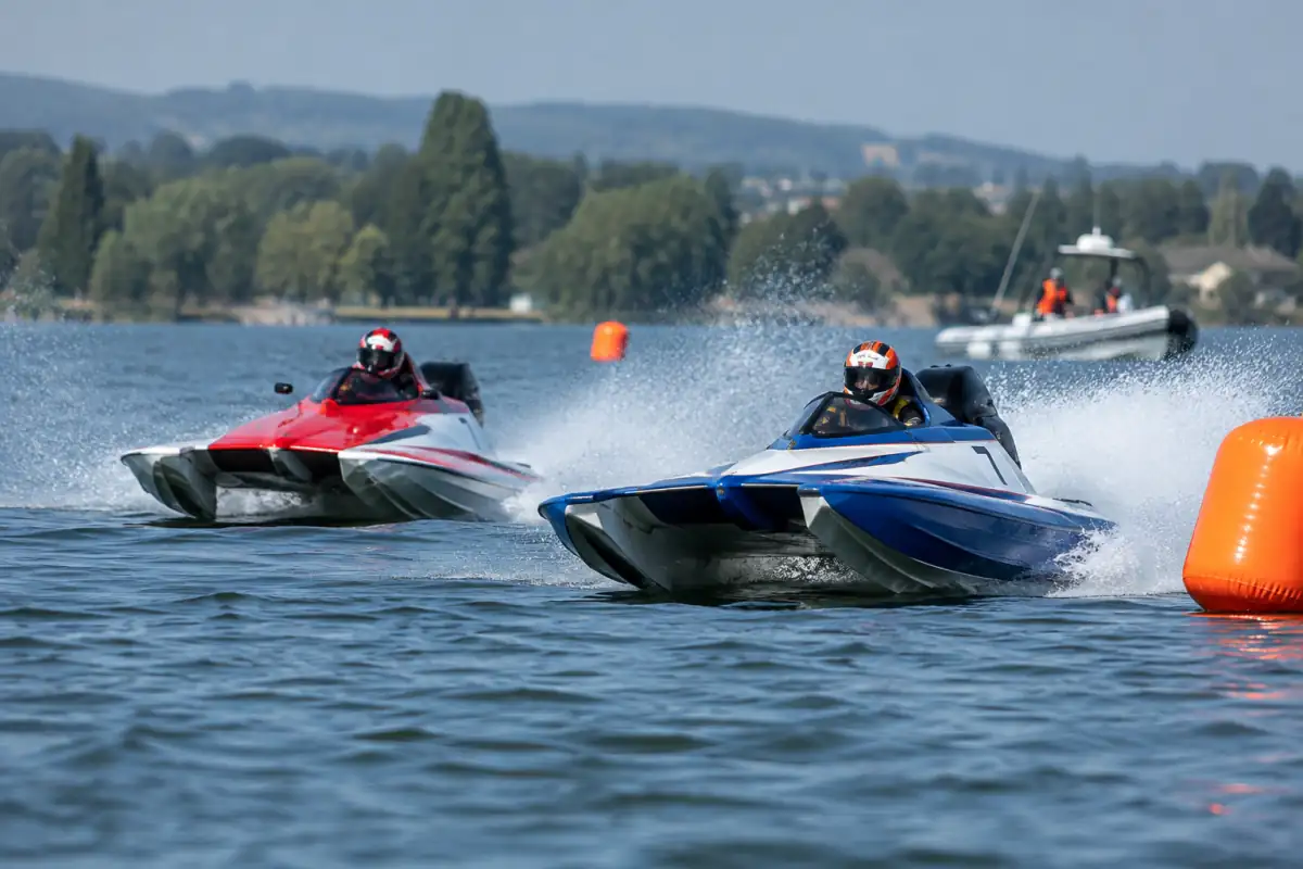 Deux bateaux de motonautisme de circuit négocient un virage entre des bouées sur un plan d’eau, pilotes équipés.