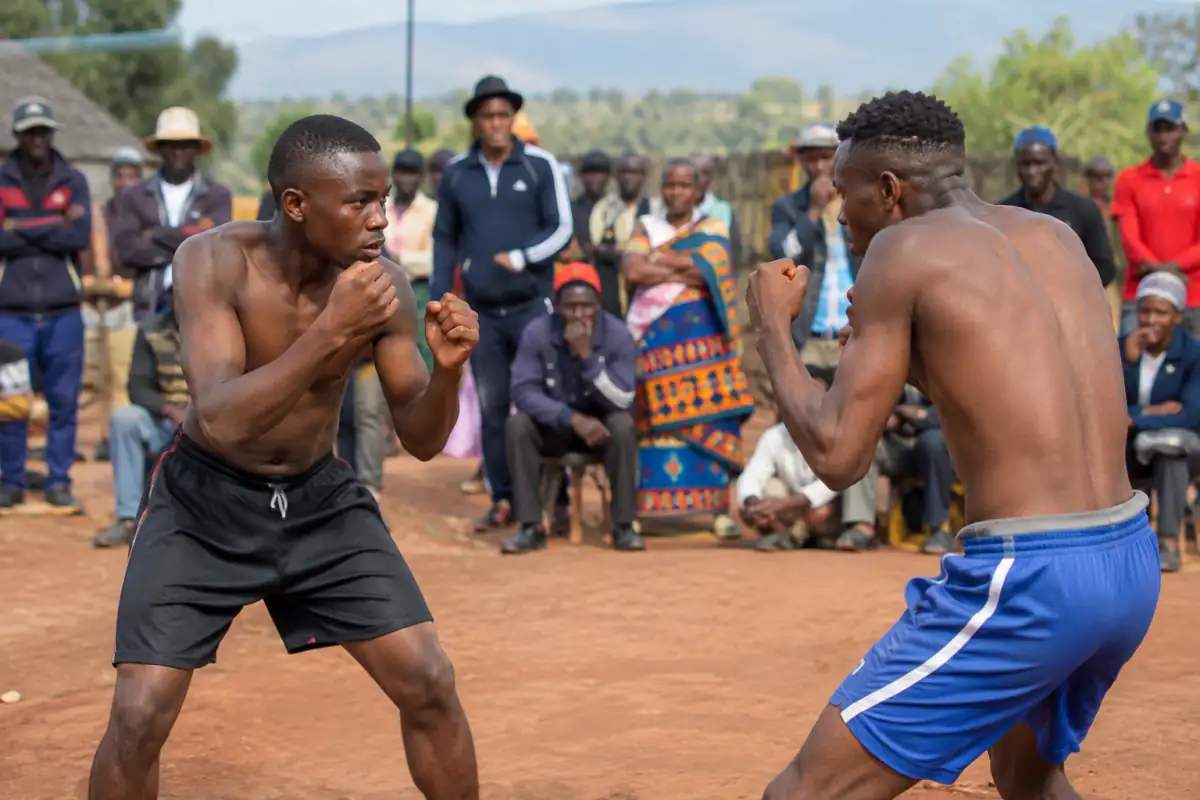 Deux adultes se font face lors d’une démonstration de musangwe à mains nues sur un terrain ouvert en Afrique du Sud.