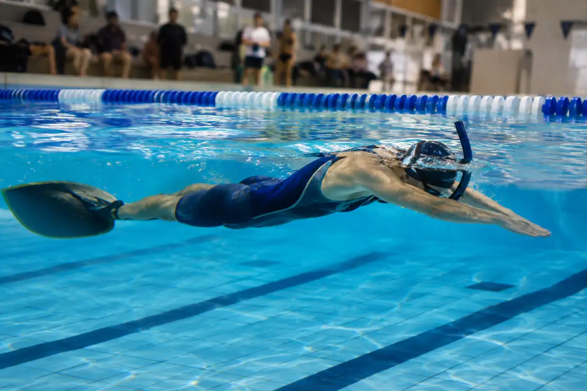 Nageur en monopalme et tuba frontal propulsé à la surface d’une piscine pendant une épreuve de nage avec palmes.