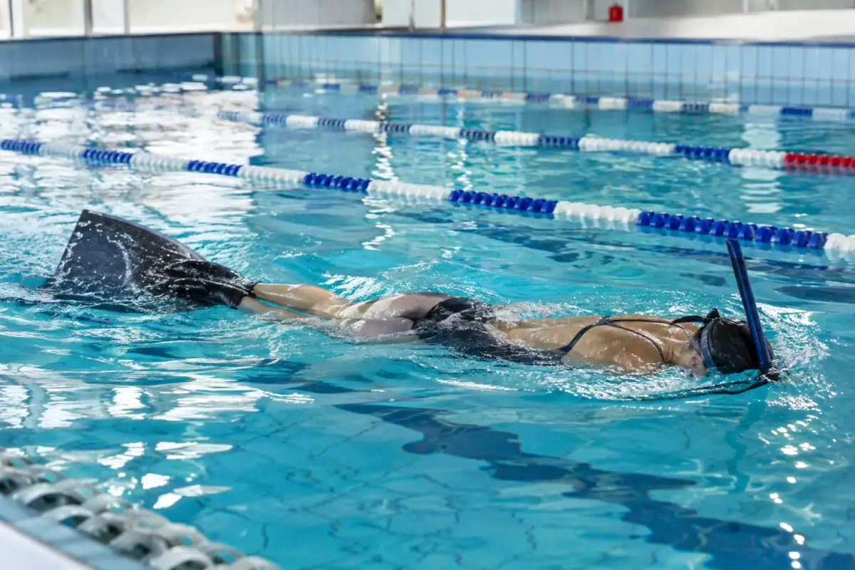 Nage avec palmes en piscine : un nageur équipé d’une monopalme et d’un tuba frontal avance en ondulant.