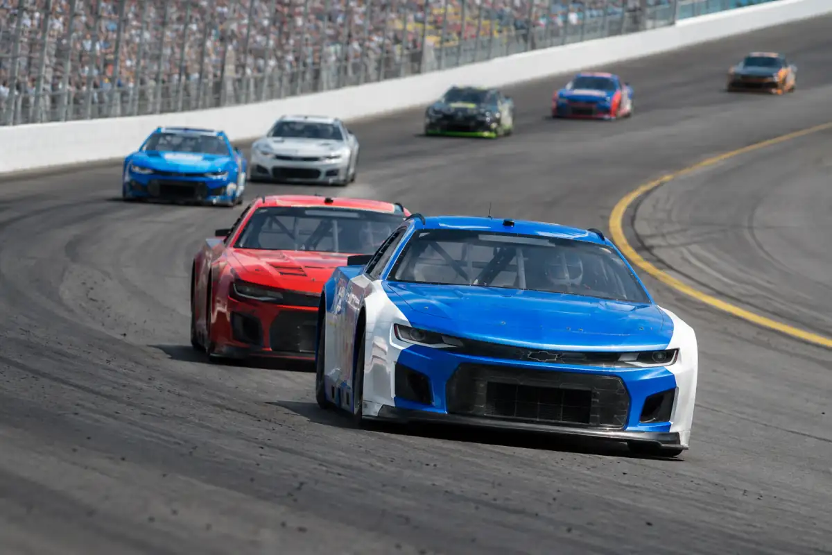 Deux stock-cars roulent en file sur un virage incliné, illustrant l’aspiration et le vocabulaire des courses NASCAR sur ovale.