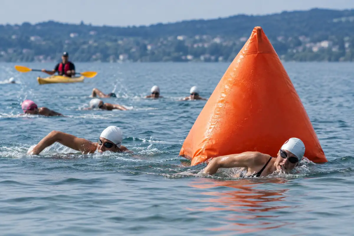 Des nageurs contournent une bouée de course en eau libre en laissant de l’espace pour dépasser sans couper le parcours.