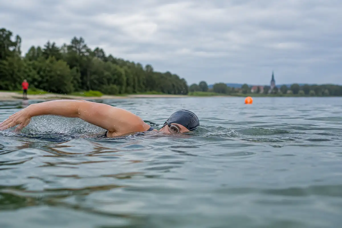 Nageur en crawl relève brièvement les yeux pour aligner une bouée avec un repère fixe sur la rive.