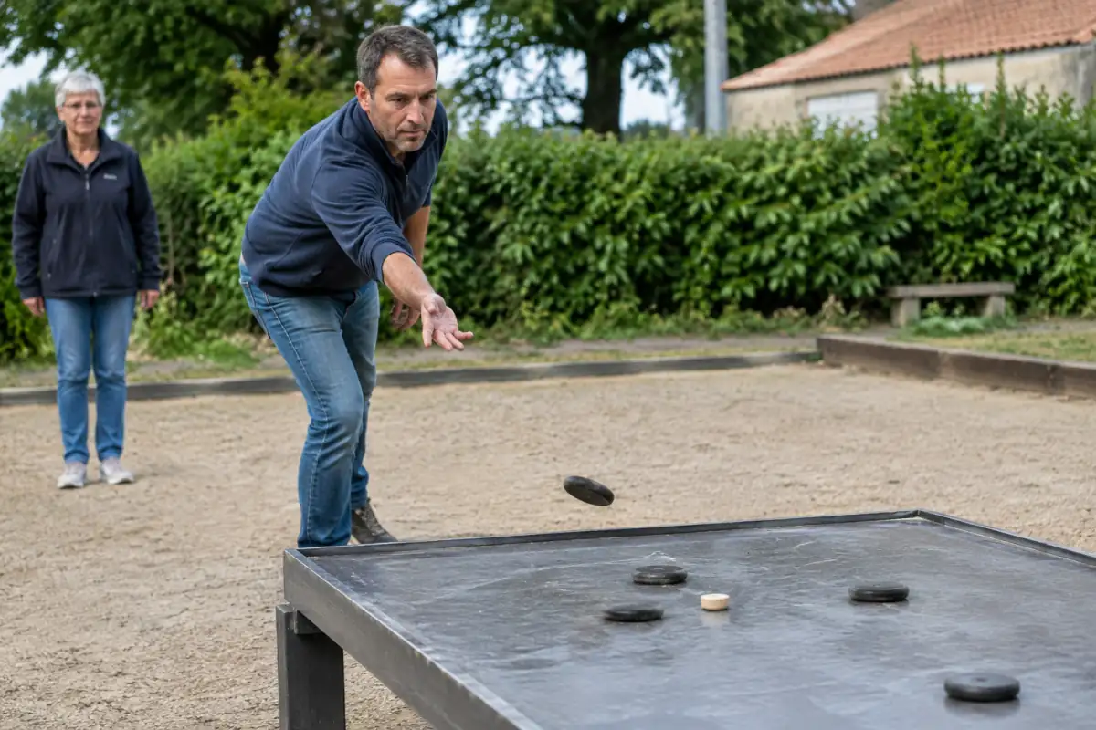 Un joueur lance un palet en fonte vers le maître posé sur une planche de plomb lors d’une partie de palet vendéen.
