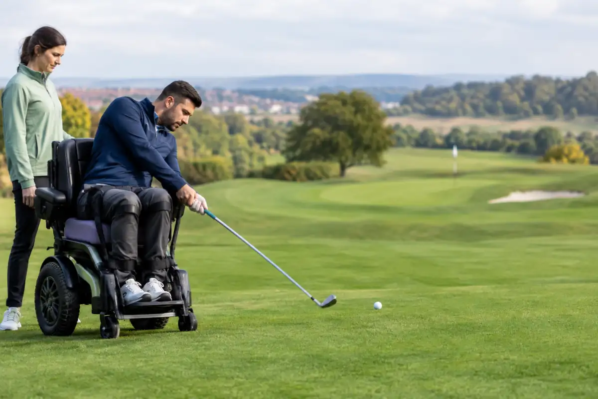 Un joueur de para-golf frappe une balle depuis un fauteuil de golf adapté sur un parcours en plein air.