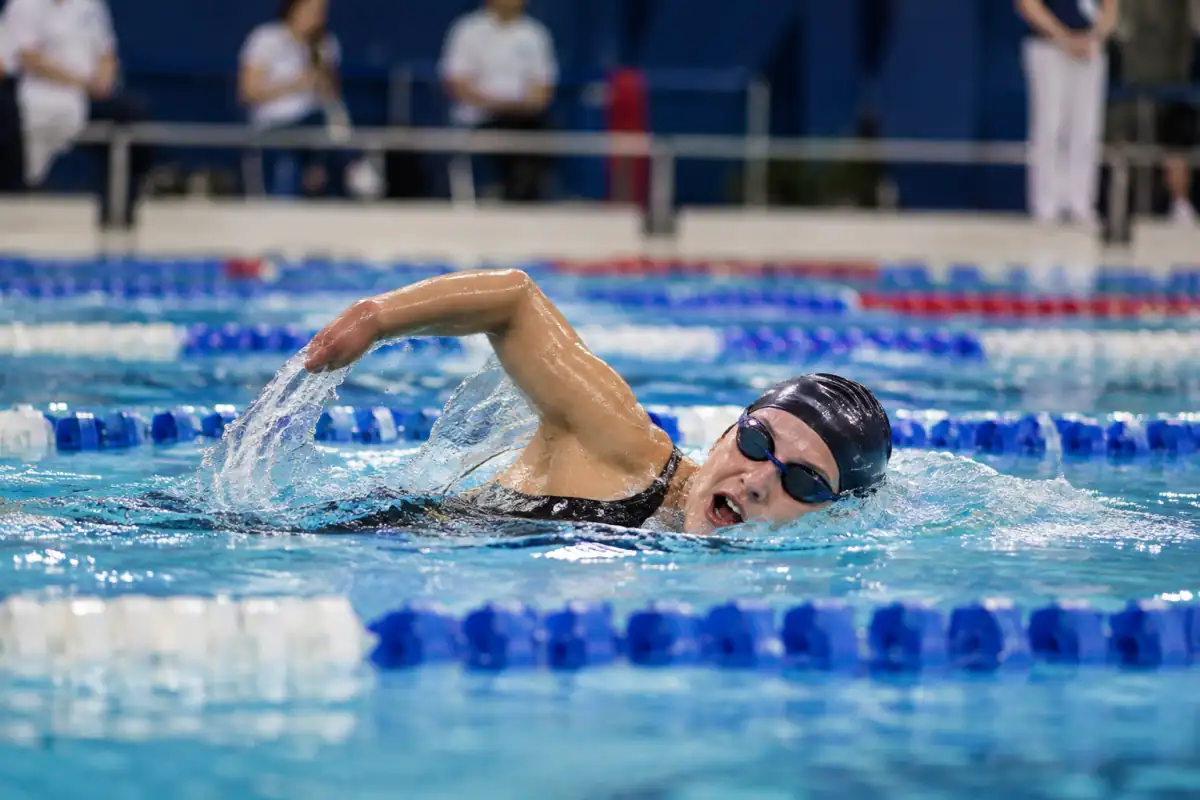 Nageur en para-natation engagé en crawl dans un couloir de piscine, avec bonnet, lunettes et lignes d’eau de compétition.