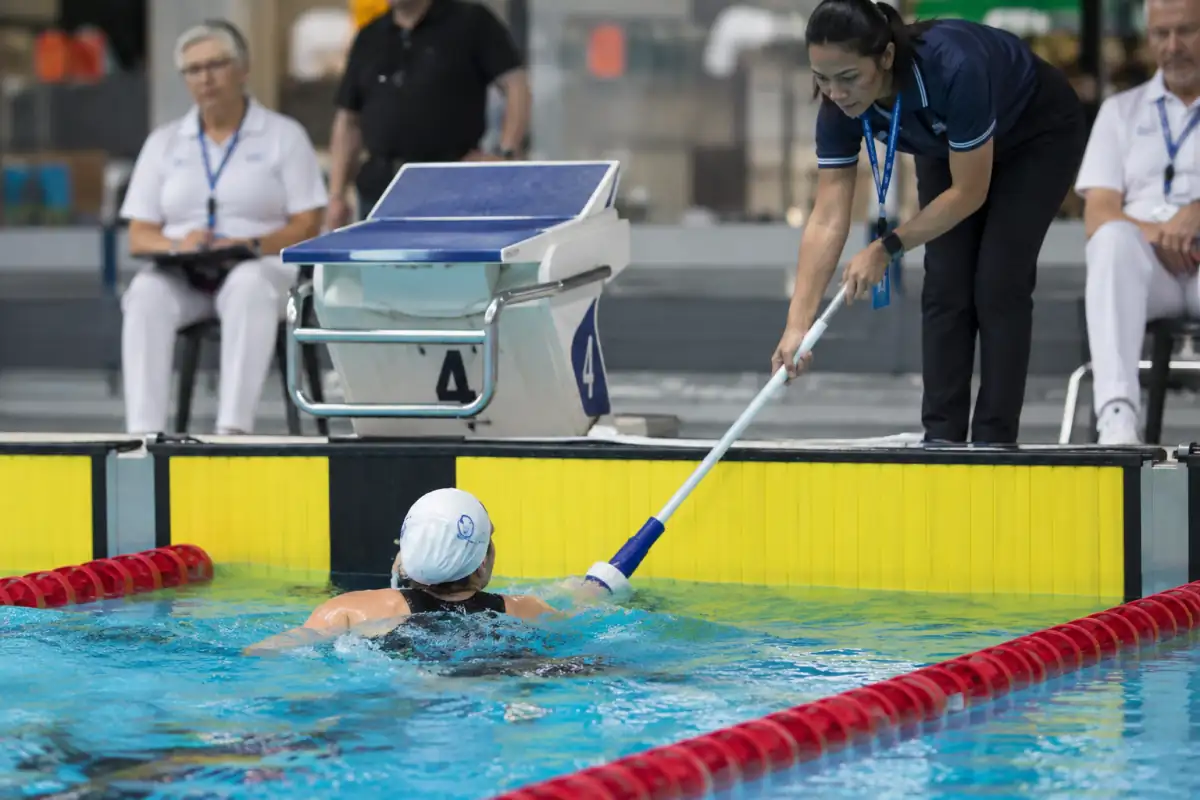 Un tapper utilise une perche à embout souple pour avertir un nageur de para-natation à l’approche du mur.