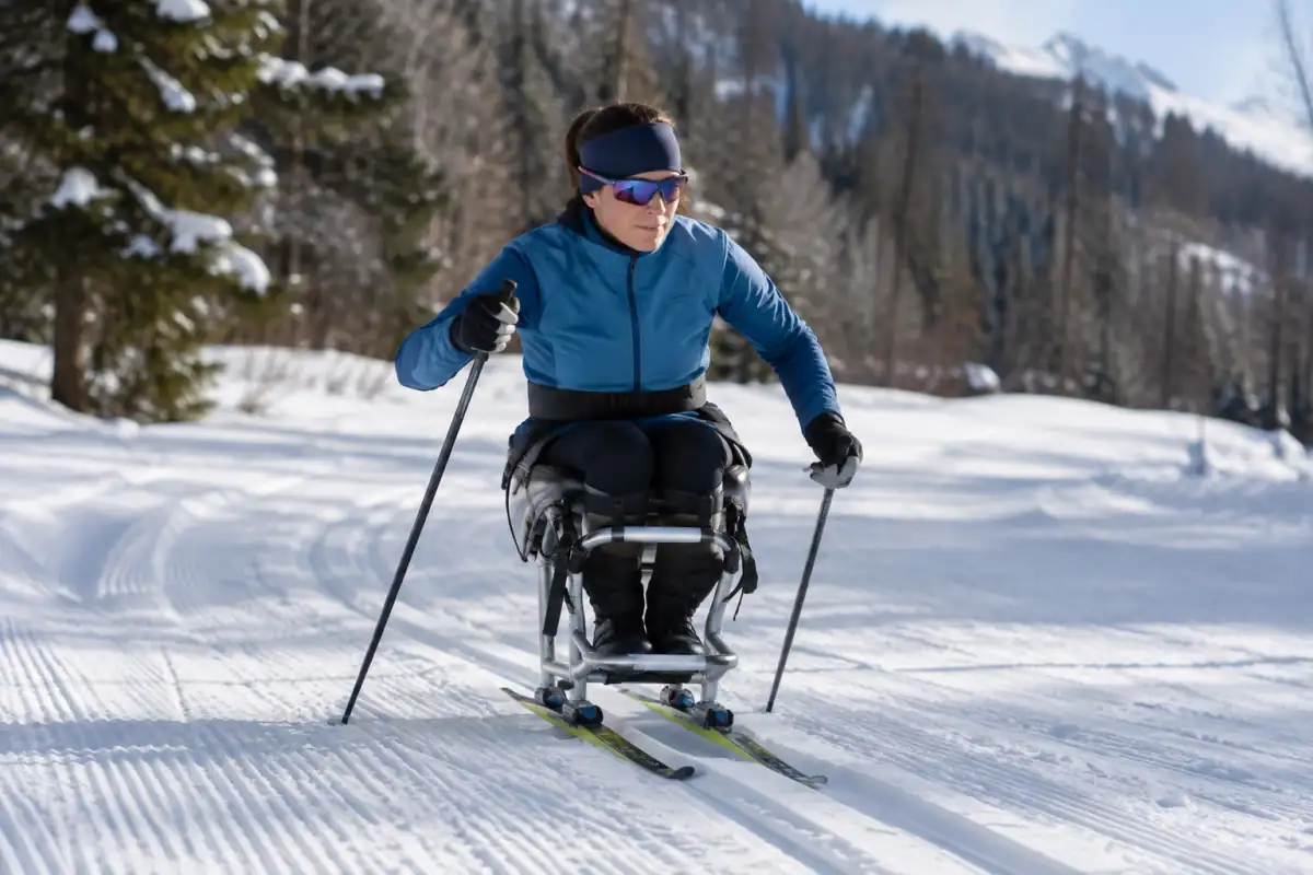 Athlète en luge nordique propulsée aux bâtons sur une piste enneigée lors d’une séance de para ski nordique.