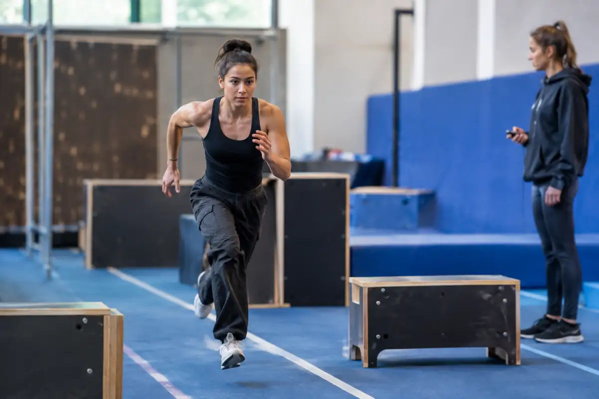 Athlète en accélération sur un parcours de speed parkour balisé, sous le regard d’un juge placé hors de la trajectoire.