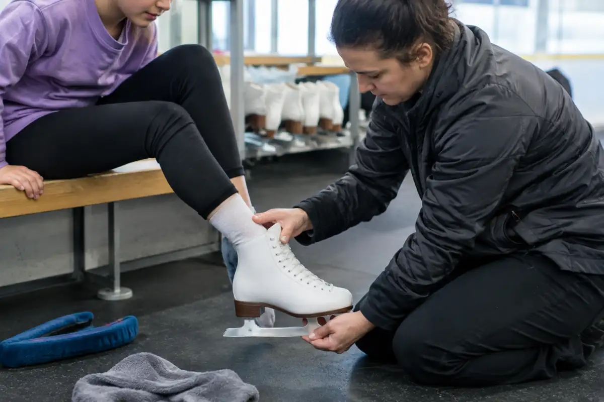 Un spécialiste ajuste le laçage d’un patin artistique débutant et vérifie le maintien du talon avant l’essai sur glace.