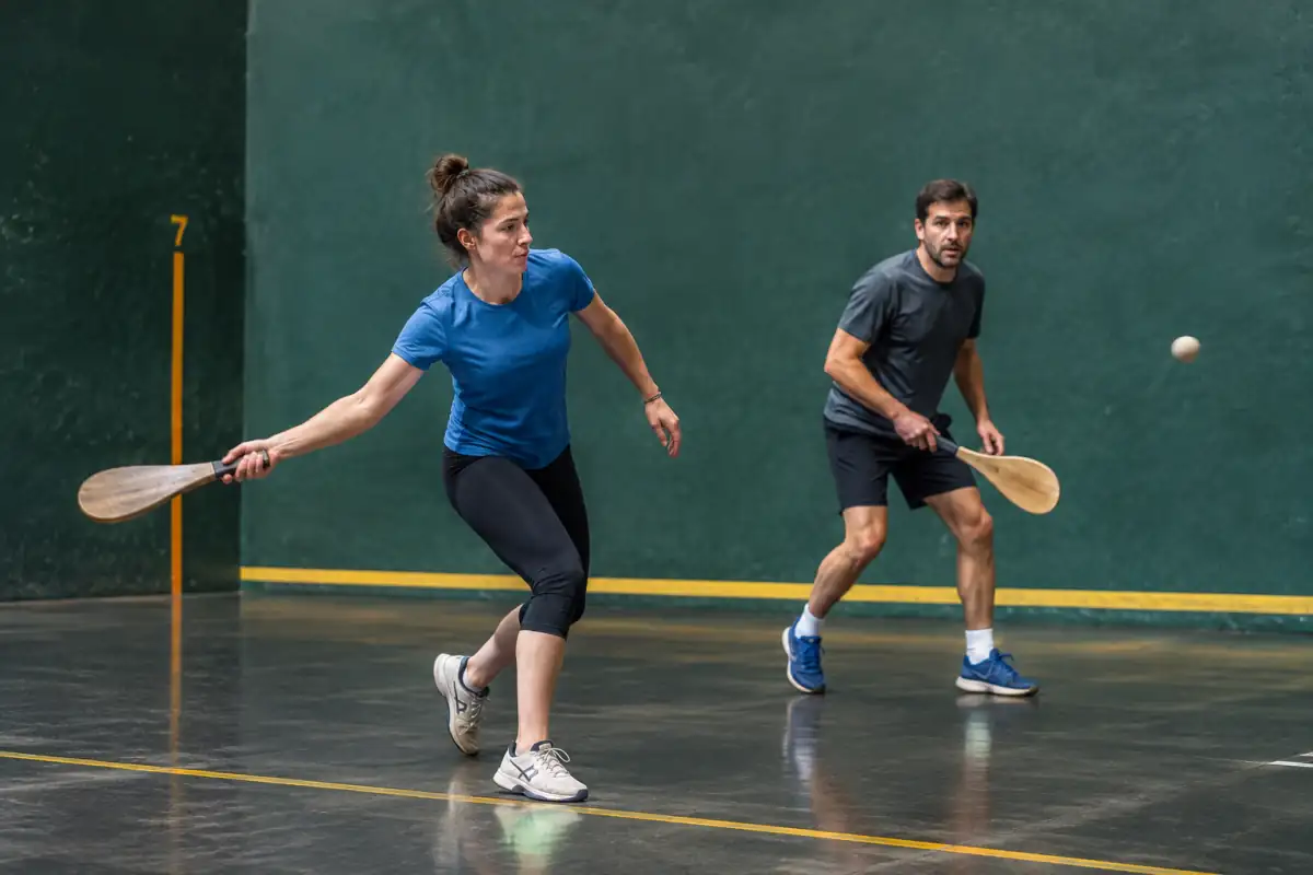 Deux joueurs de pelote basque travaillent le replacement et la régularité lors d’un exercice en binôme sur un fronton.
