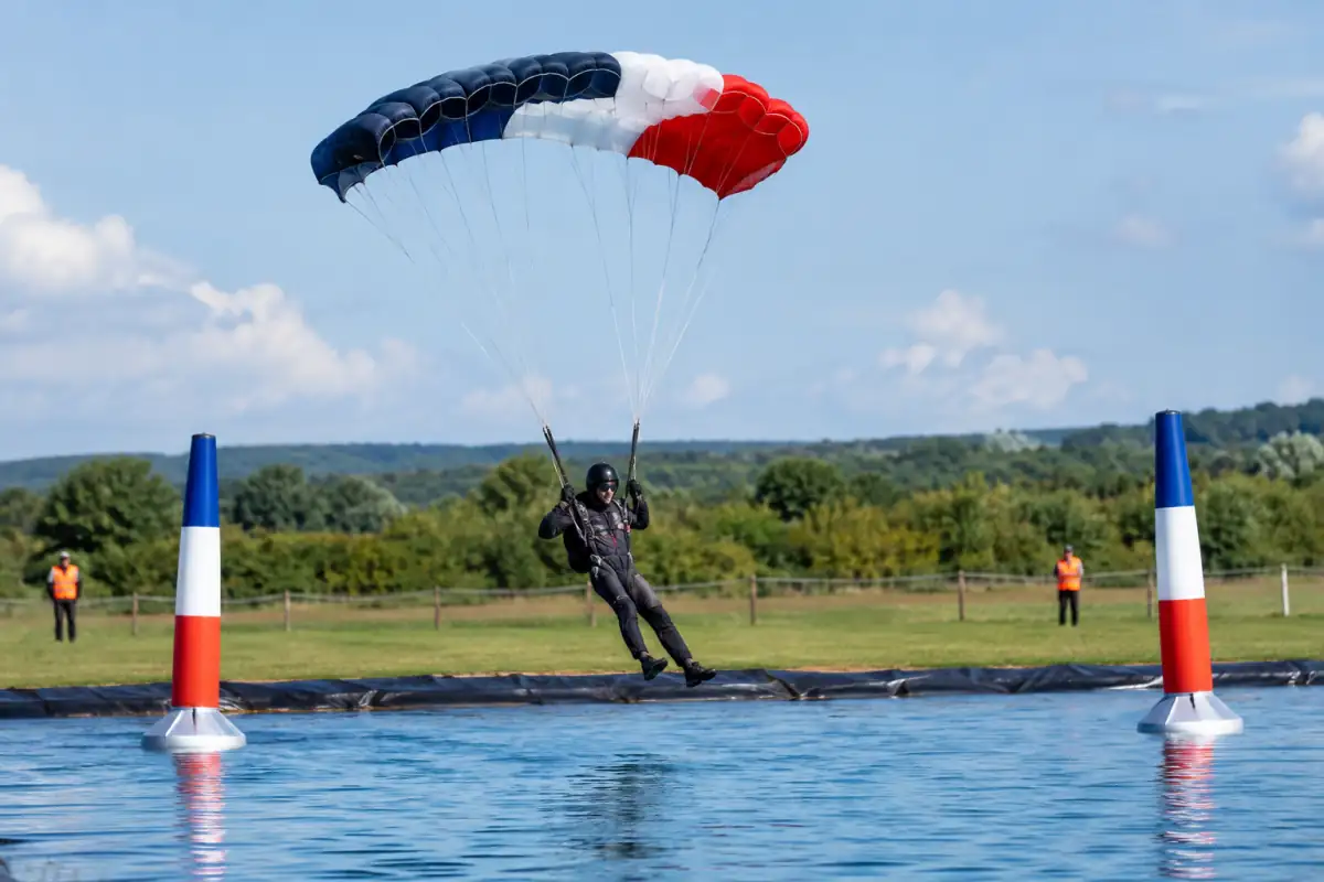 Un parachutiste pilote une voile rapide au-dessus d’un parcours aquatique lors d’une épreuve de pilotage sous voile.