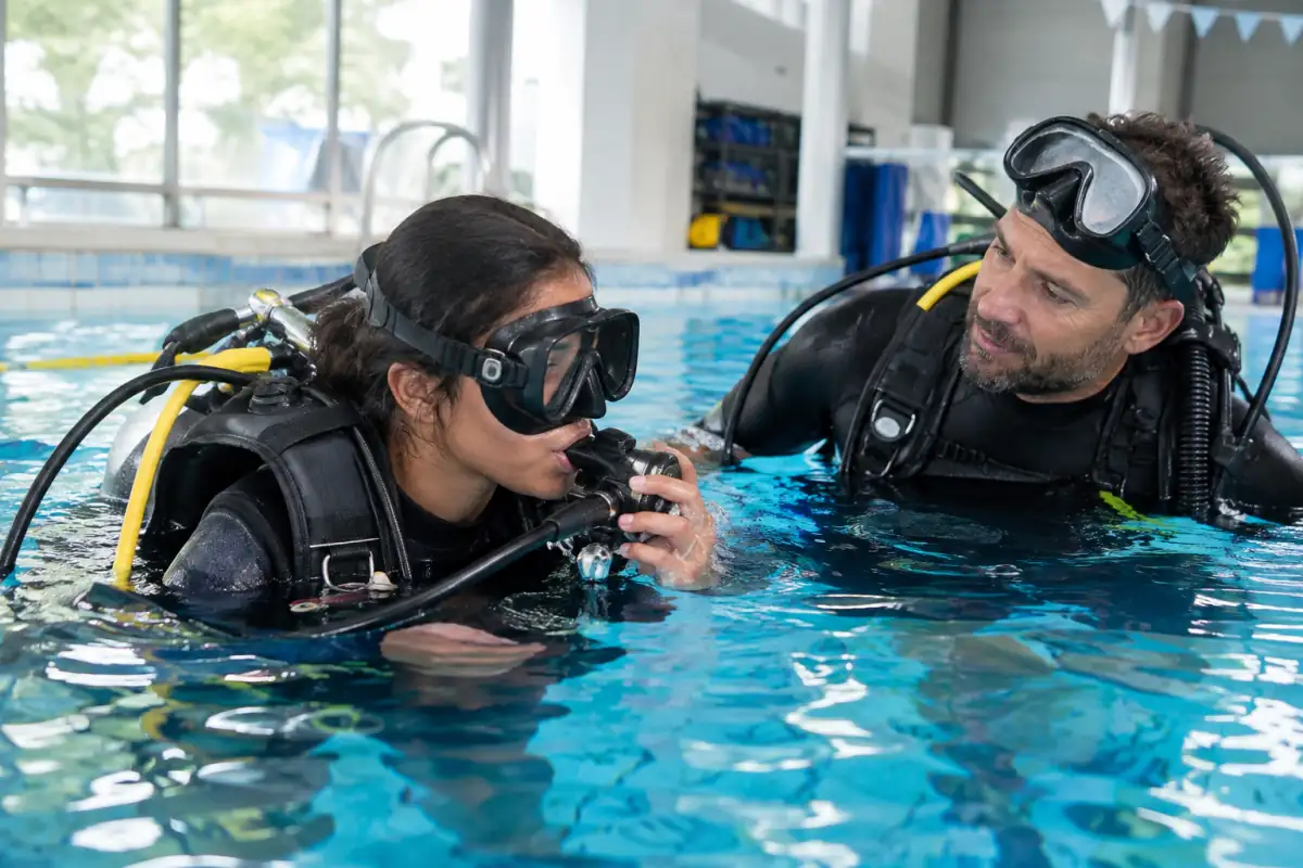 Un moniteur accompagne une débutante lors d’un exercice de respiration et de vidage de masque en piscine.