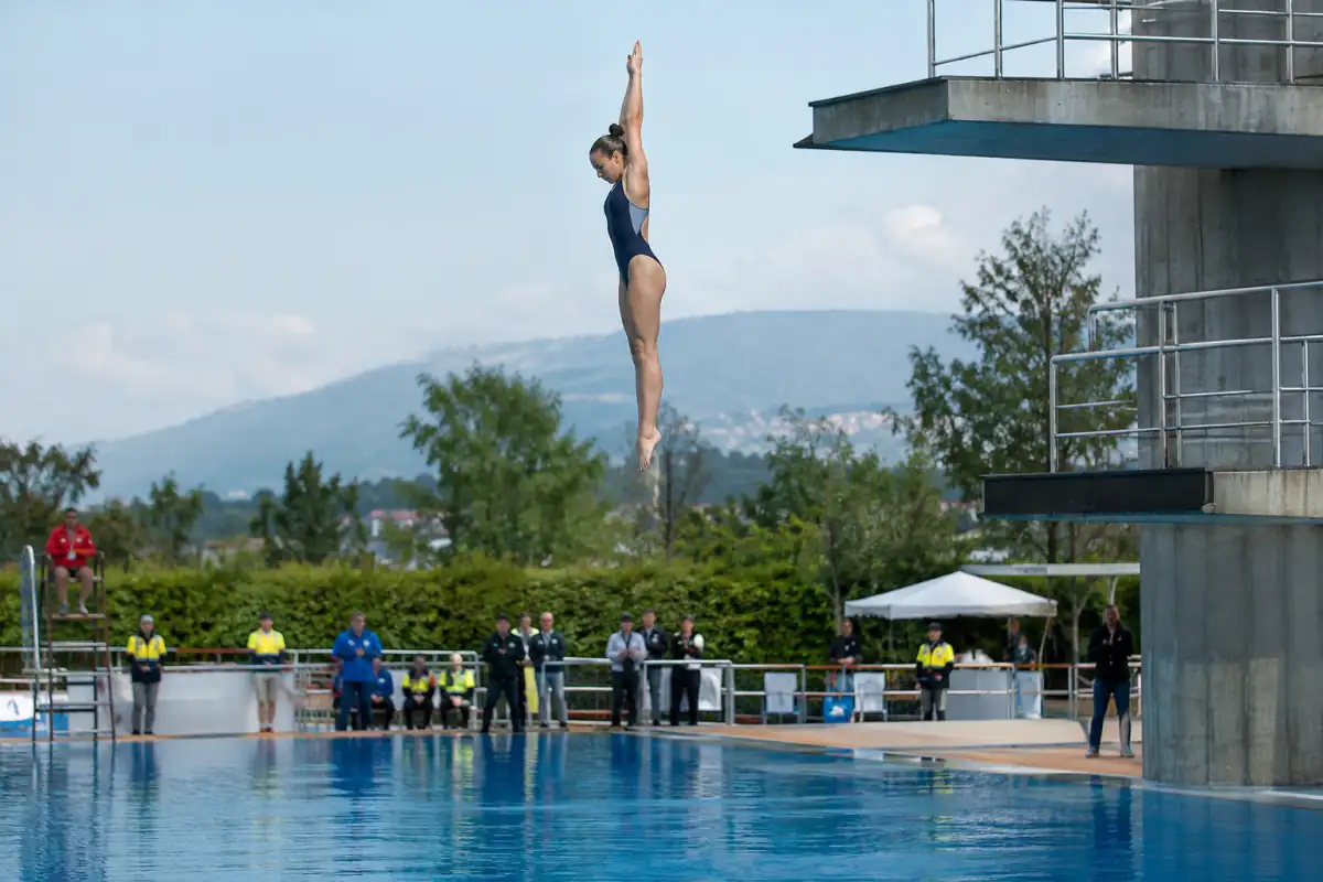 Plongeur de haut vol en position verticale, pieds en premier, lors d’un saut depuis une plateforme élevée.