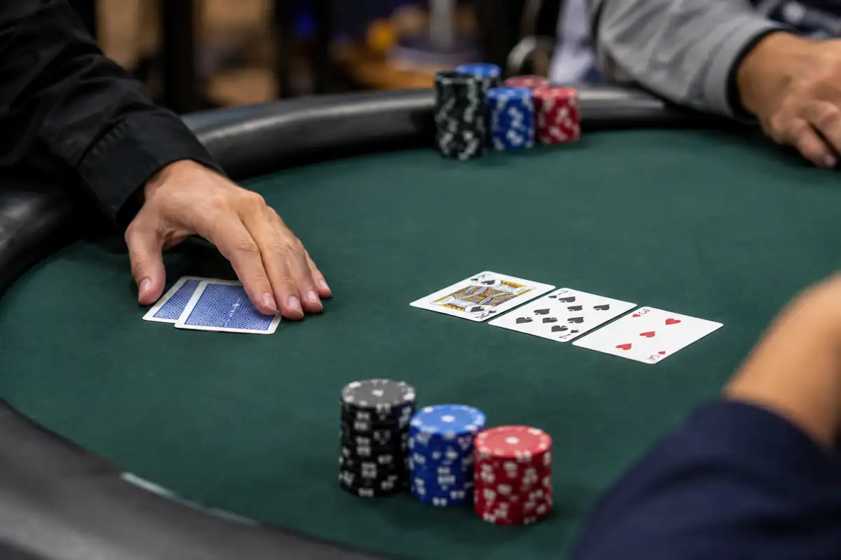 Main de Texas hold’em en tournoi avec deux cartes privatives, le flop au centre de la table et des jetons empilés.