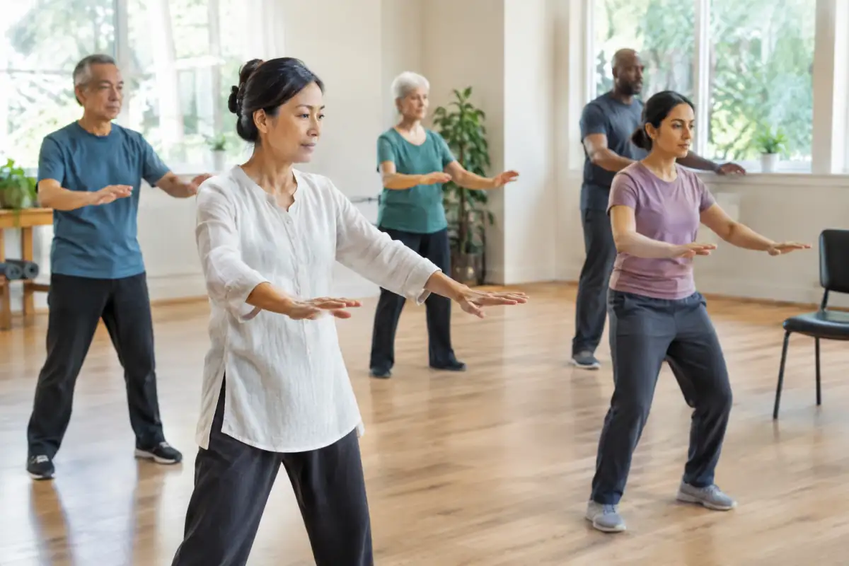 Un enseignant montre un mouvement lent de qi gong à un débutant dans une salle de cours lumineuse.