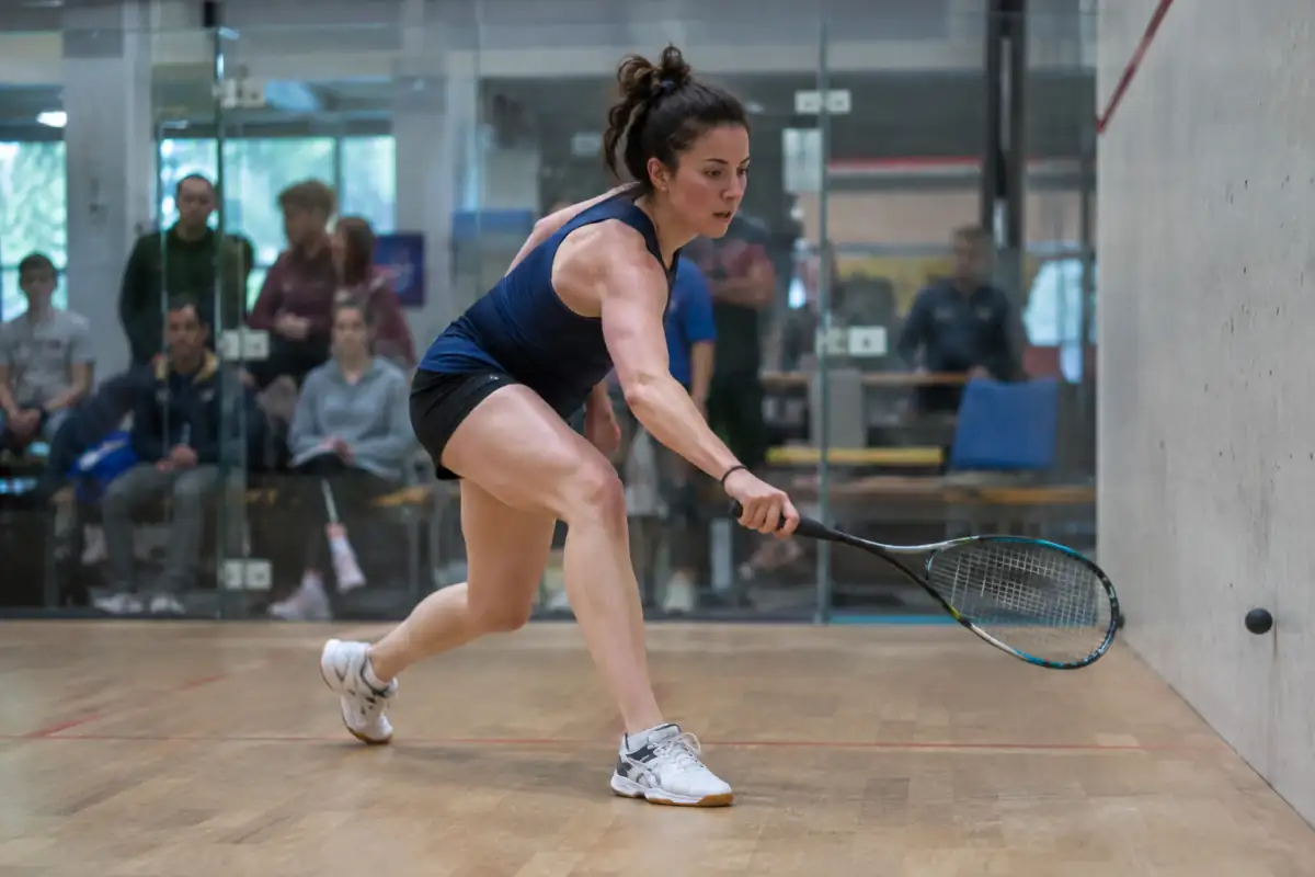 Un joueur frappe une balle en squash pendant une rencontre de racketlon, qui enchaîne quatre sports de raquette.