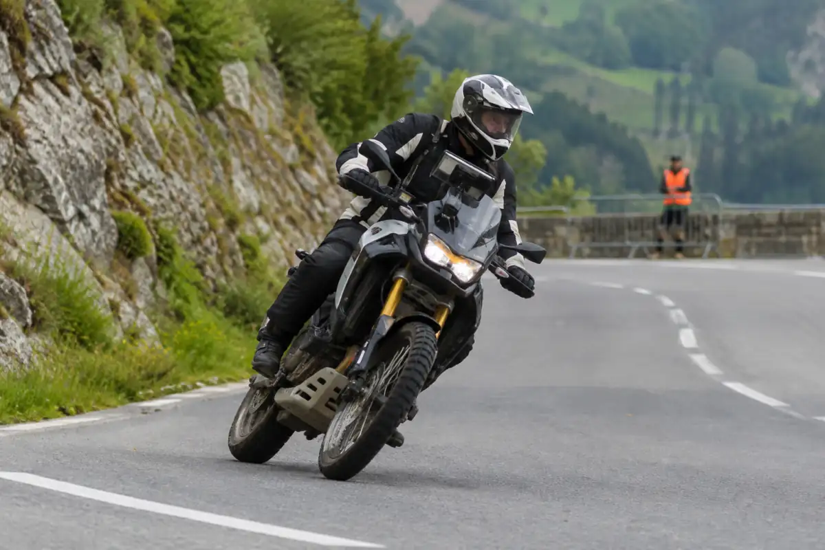 Pilote en tenue de protection négociant un virage sur une spéciale fermée lors d’un rallye routier moto.