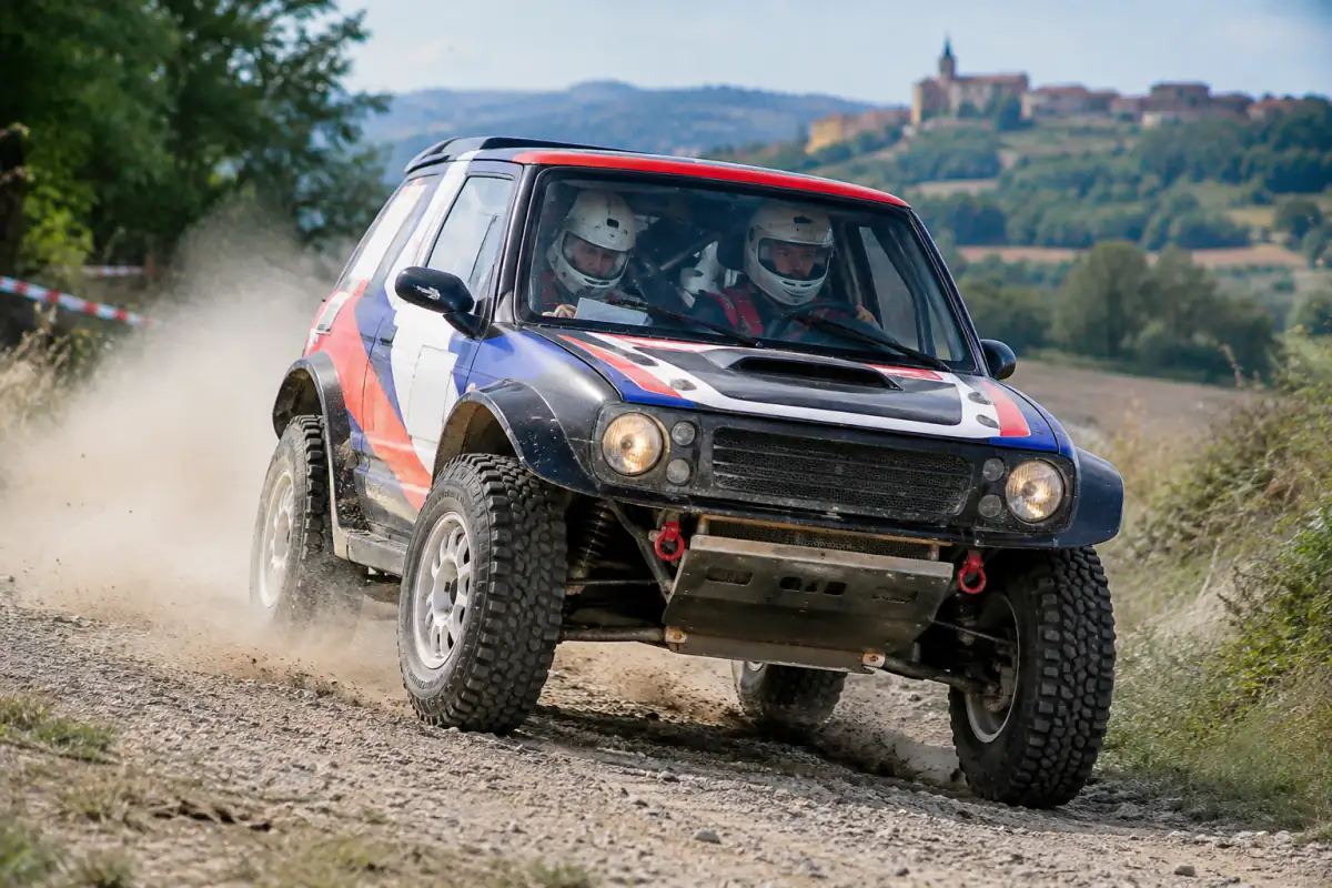 Une voiture de rallye tout-terrain pilotée par un équipage file sur une piste de gravier en France.