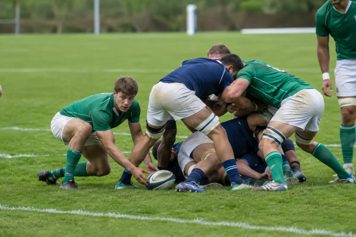Un ruck se forme après un plaquage : les joueurs restent debout au-dessus du ballon pendant que le demi de mêlée se prépare à le jouer.