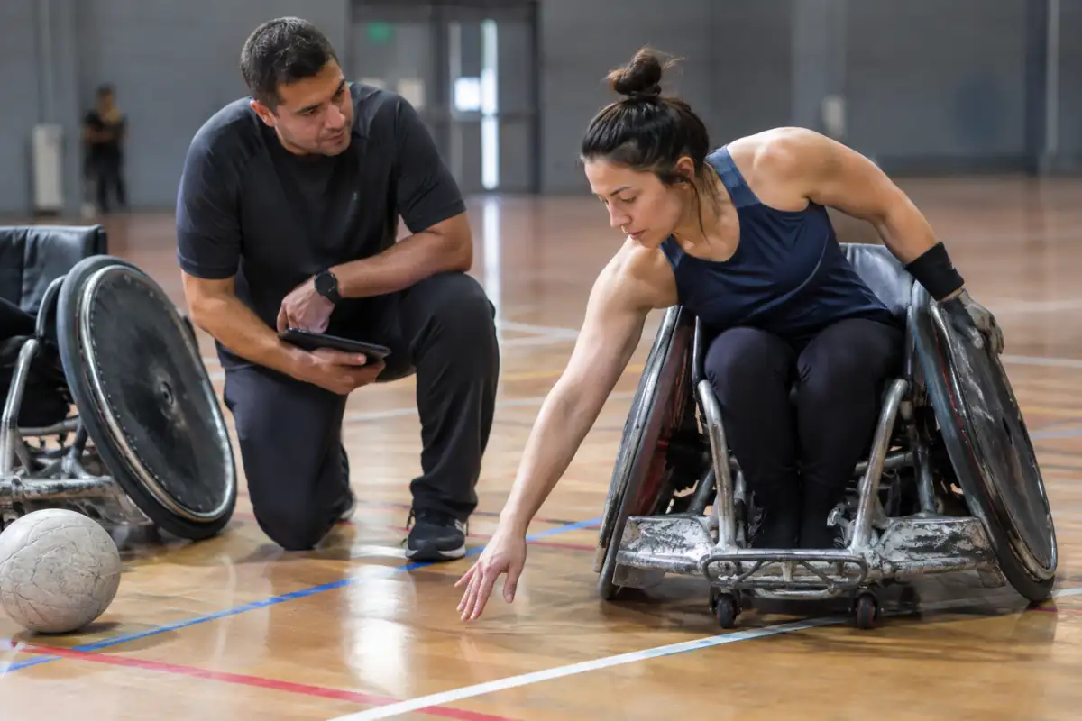 Un classificateur observe le contrôle du tronc et le mouvement du bras d’un joueur de rugby fauteuil dans un gymnase.
