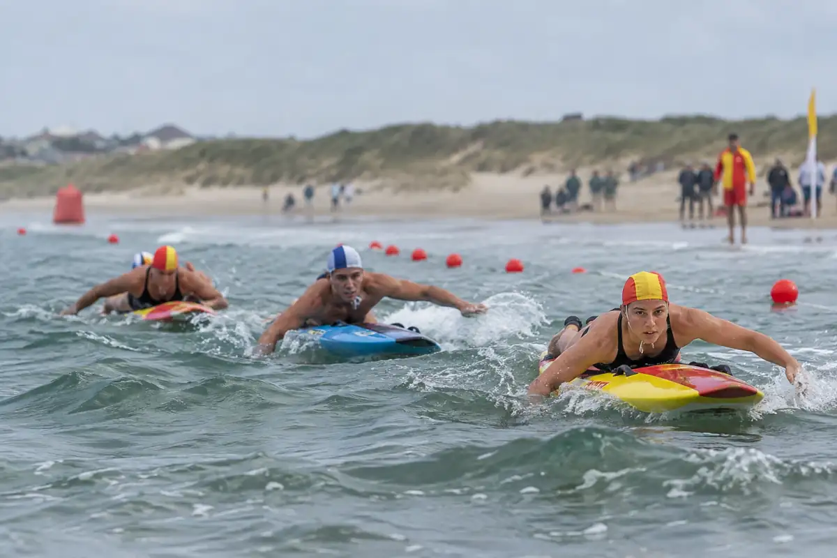 Épreuve de sauvetage sportif côtier : des athlètes pagaient sur leurs planches de sauvetage dans les vagues.