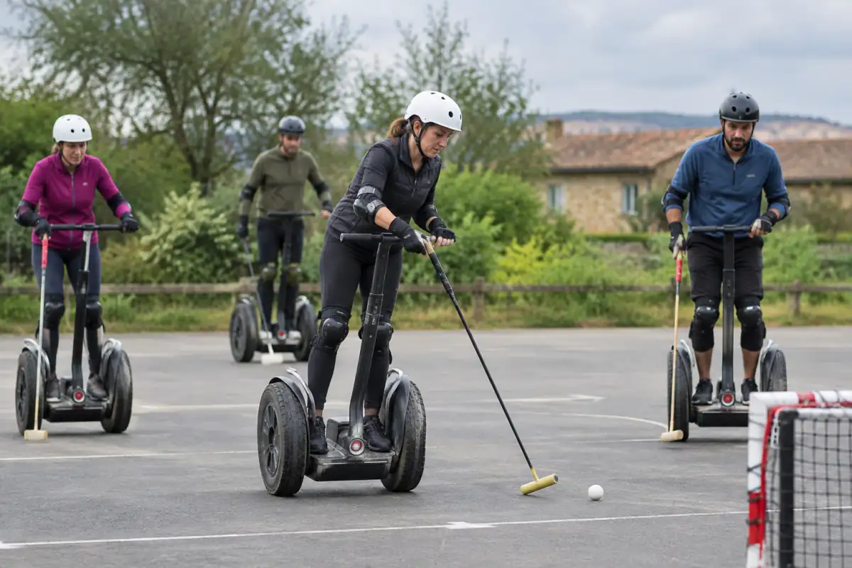 Joueurs de segway polo casqués sur gyropodes, maniant leur maillet sur un terrain extérieur pendant un match.