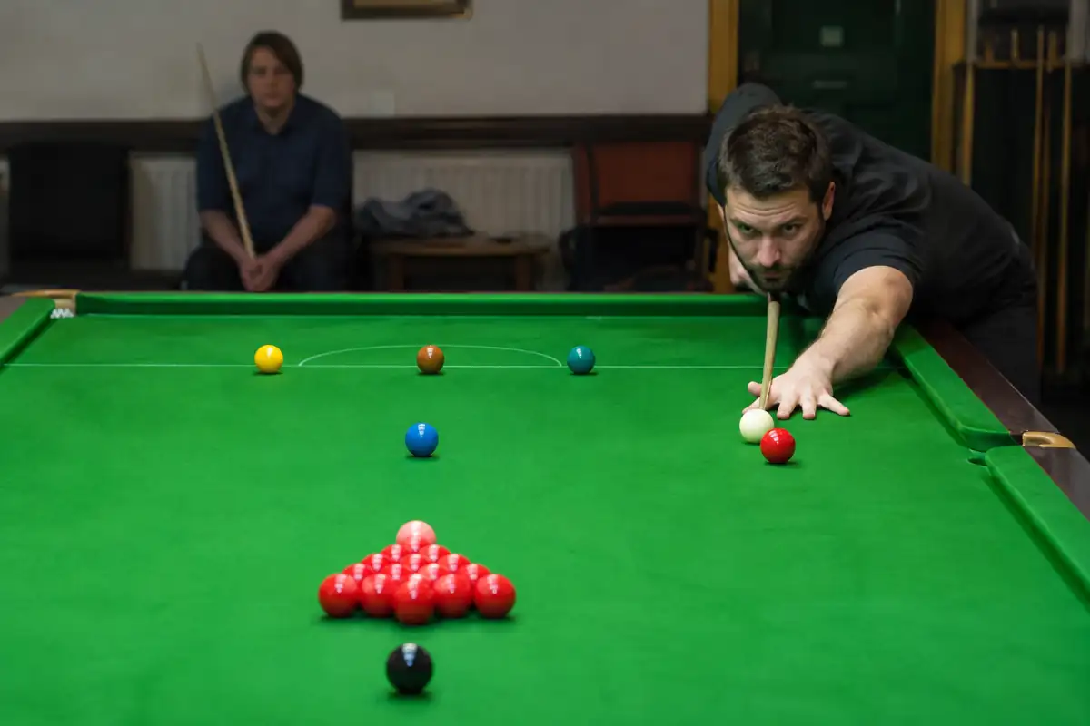 Joueur de snooker en position de sécurité, blanche près d’une rouge et couleurs disposées sur leurs repères sur le tapis vert.