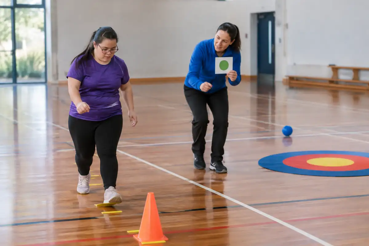 Un sportif suit un parcours court matérialisé au sol pendant qu’un éducateur montre le geste et adapte la consigne.