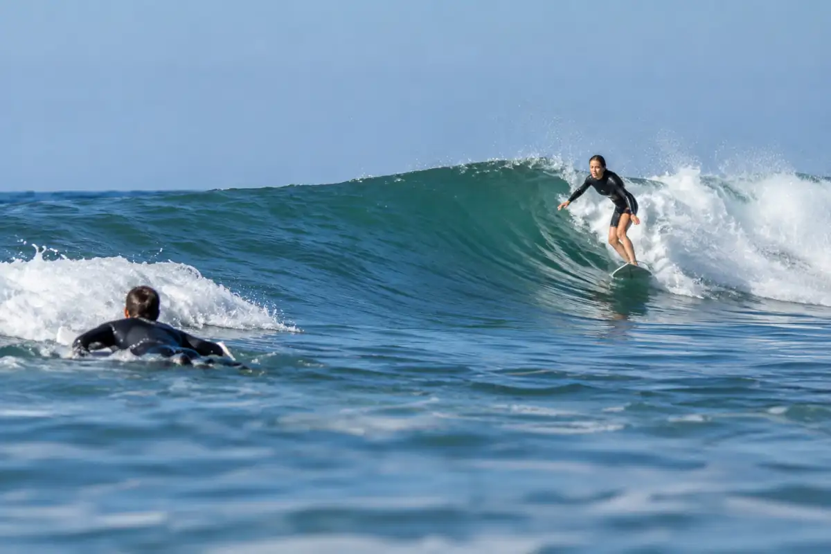 Un surfeur contourne la mousse pour rejoindre le large sans couper la trajectoire d’une personne qui descend la vague.