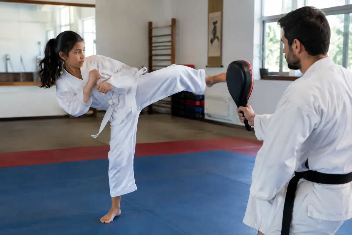 Pratiquante de taekwondo travaillant un coup de pied circulaire sur une cible tenue par un partenaire, pied d’appui en pivot.