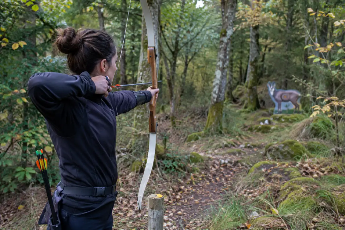 Archer visant une cible animalière sur un parcours forestier de tir à l’arc nature en France.