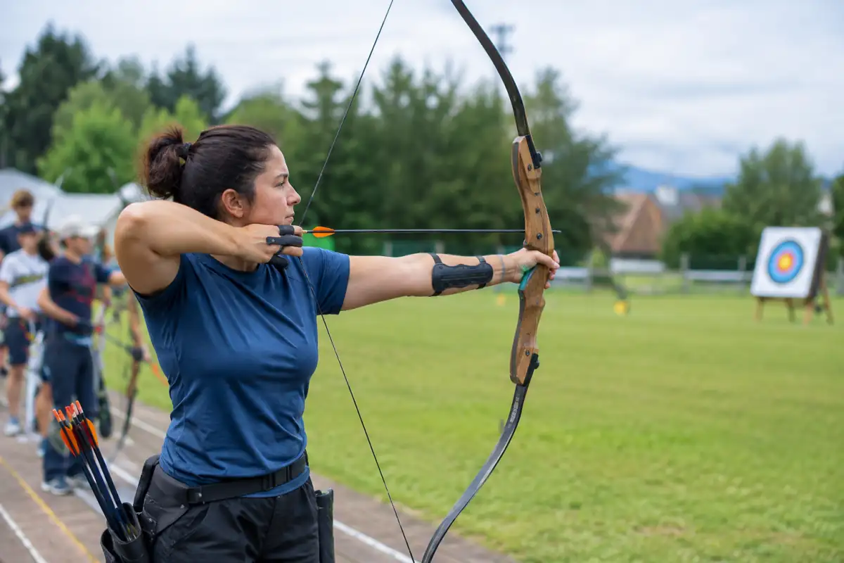 Un archer pratique le tir à l’arc nu en extérieur, avec un arc sans viseur ni stabilisateurs, face à une cible.