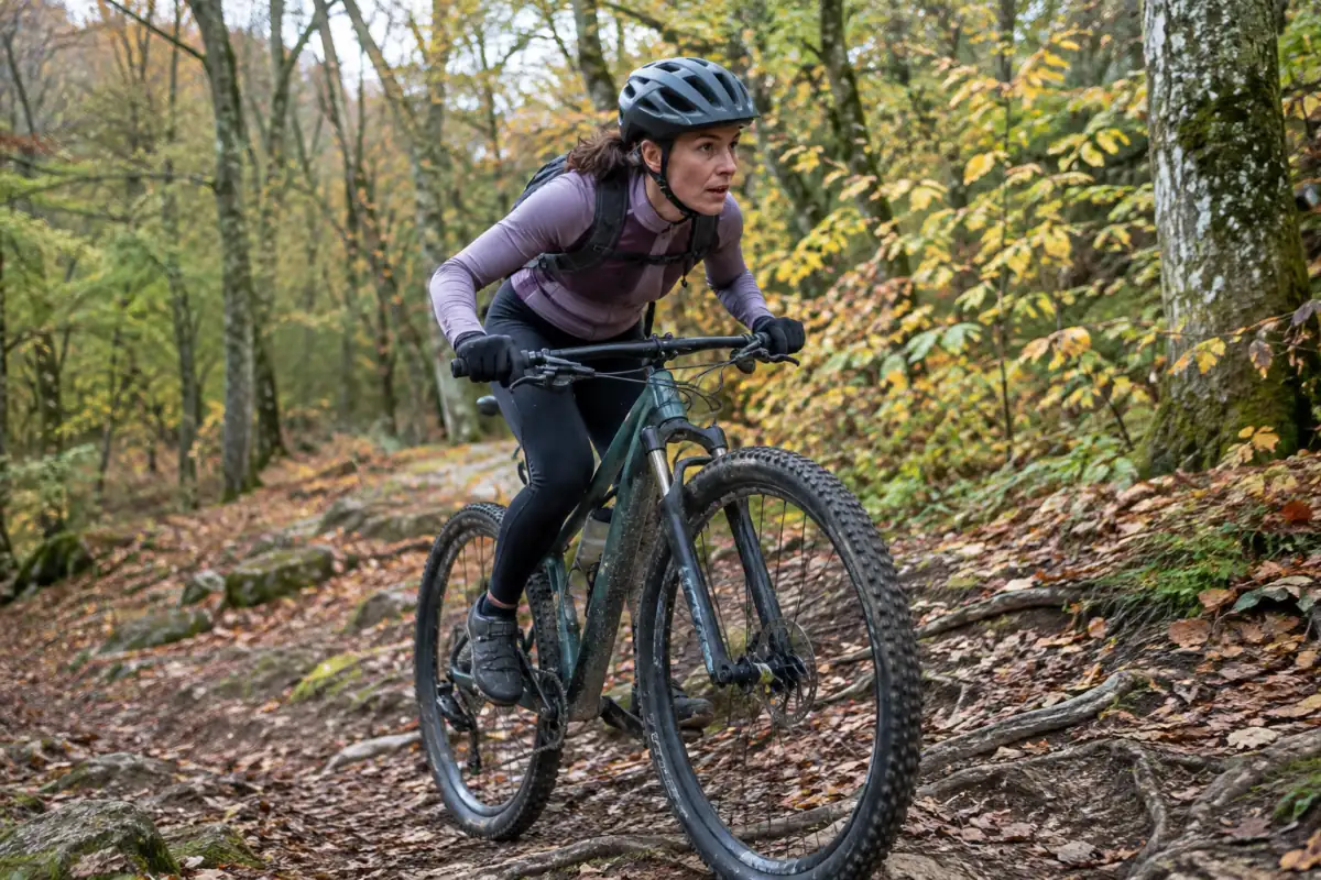 Un vététiste en casque pédale en montée sur un sentier forestier caillouteux lors d’une sortie de VTT cross-country.