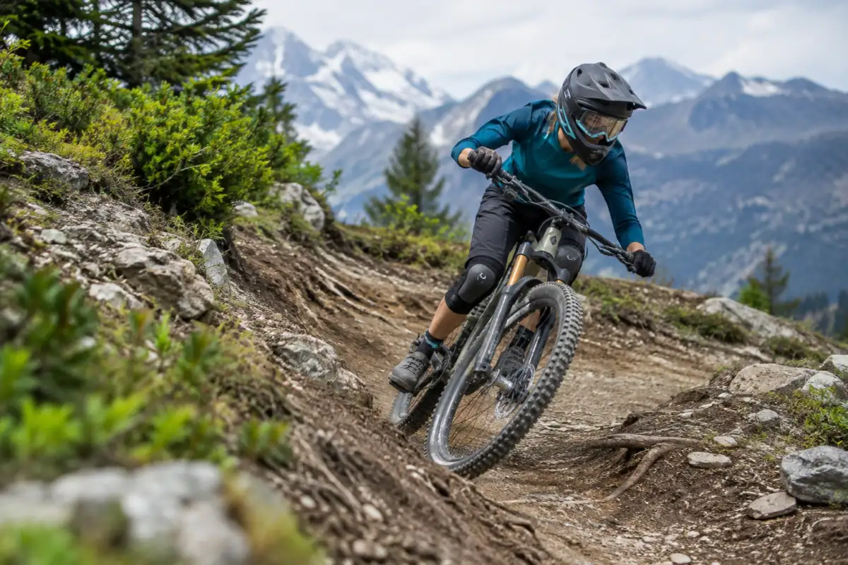VTT de descente : une personne équipée d’un casque intégral négocie un virage rocheux sur une piste de bike park alpin.